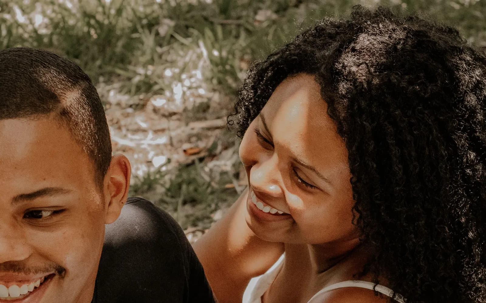 Couple afro-international riant ensemble allongé dans l'herbe